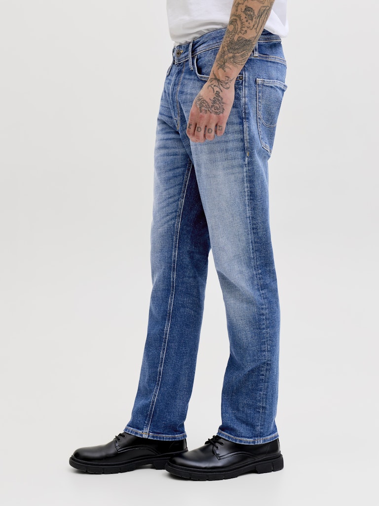 Person wearing blue jeans and black shoes on a white background