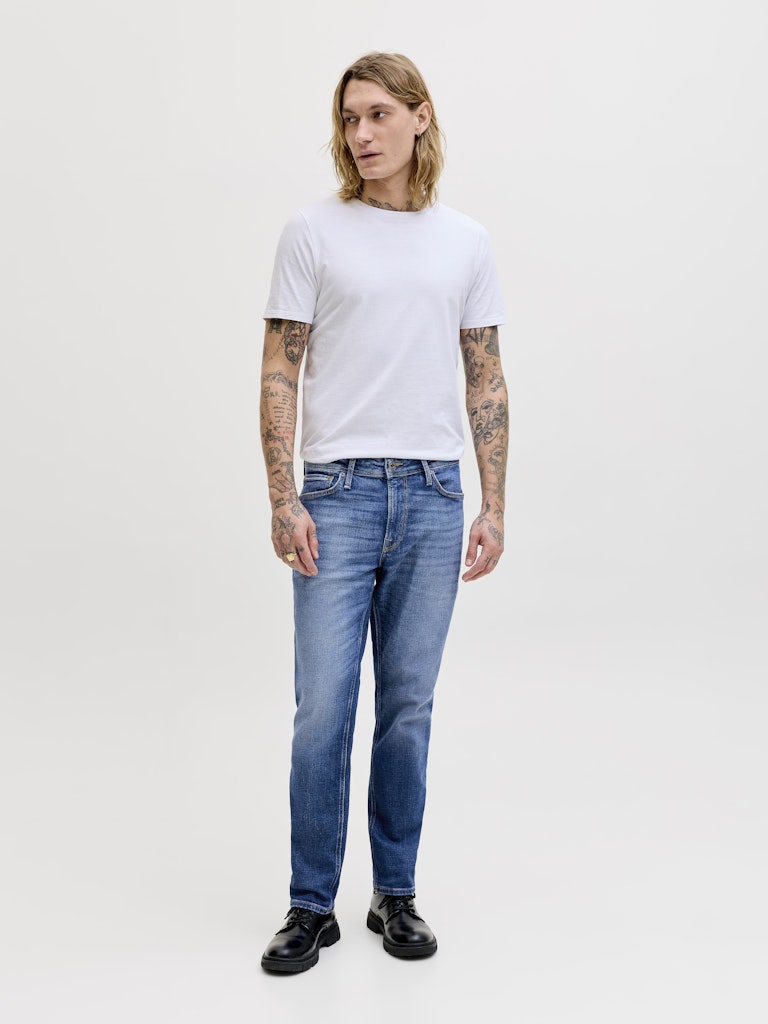 Person wearing a white t-shirt and blue jeans on a plain background