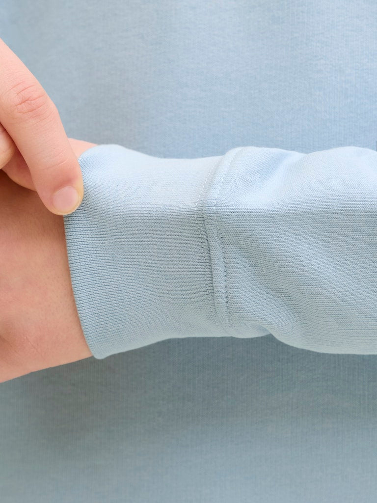 Light blue fabric with a hand holding it against a light gray background