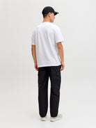 Person wearing a white t-shirt and black pants on a plain background