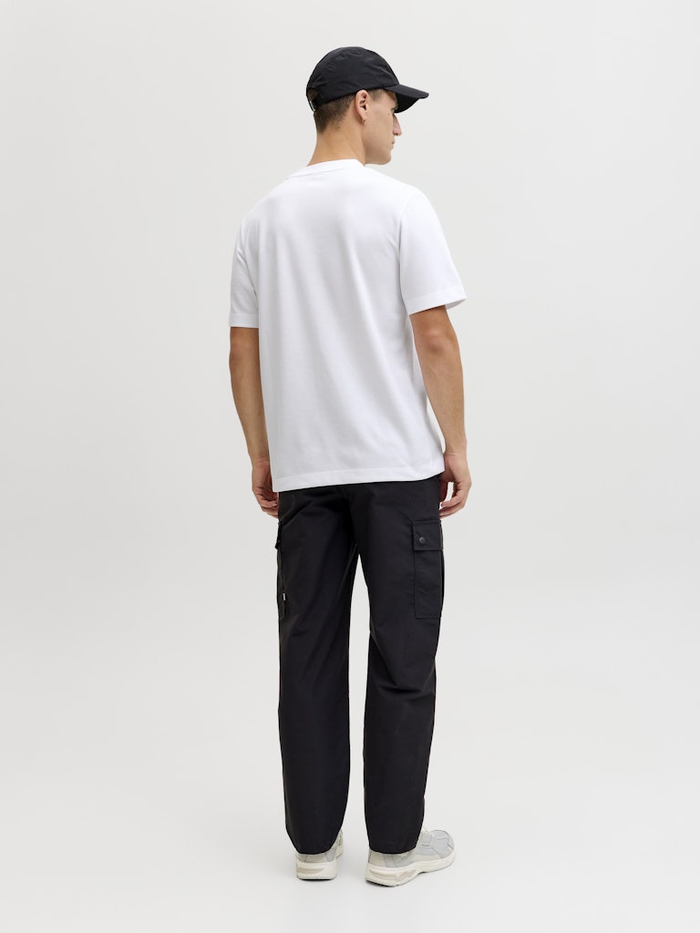 Person wearing a white t-shirt and black pants on a plain background