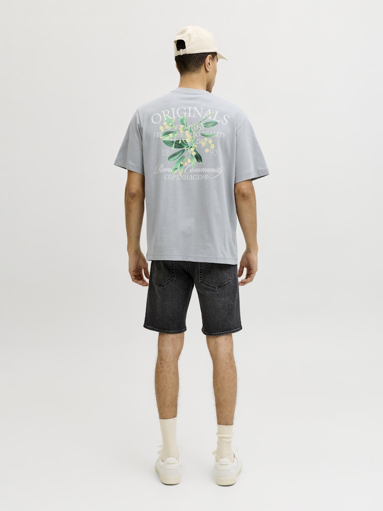 Man wearing a gray t-shirt with a floral design and text, standing against a white background