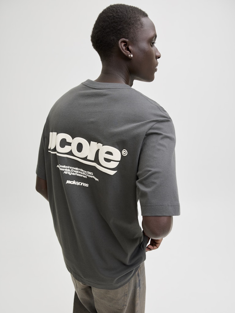 Man wearing dark grey t-shirt with 'JJCORE' backprint