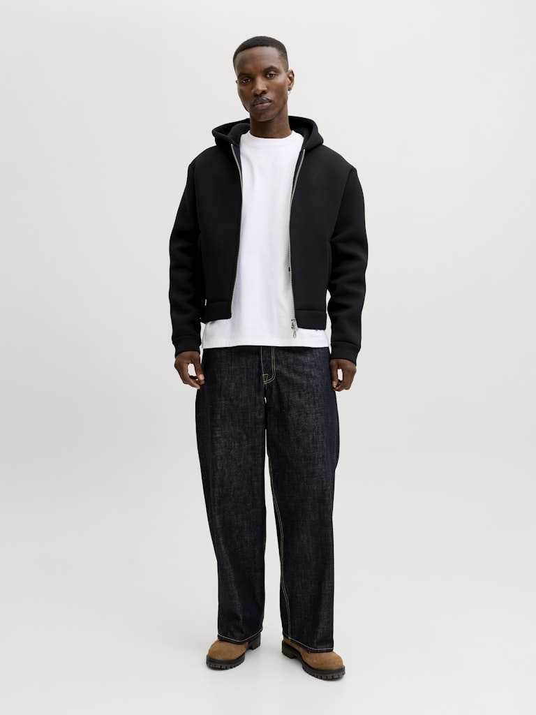 Person wearing a black hoodie, white t-shirt, and dark jeans on a white background