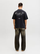 Person wearing a black t-shirt with text on the back, standing against a white background