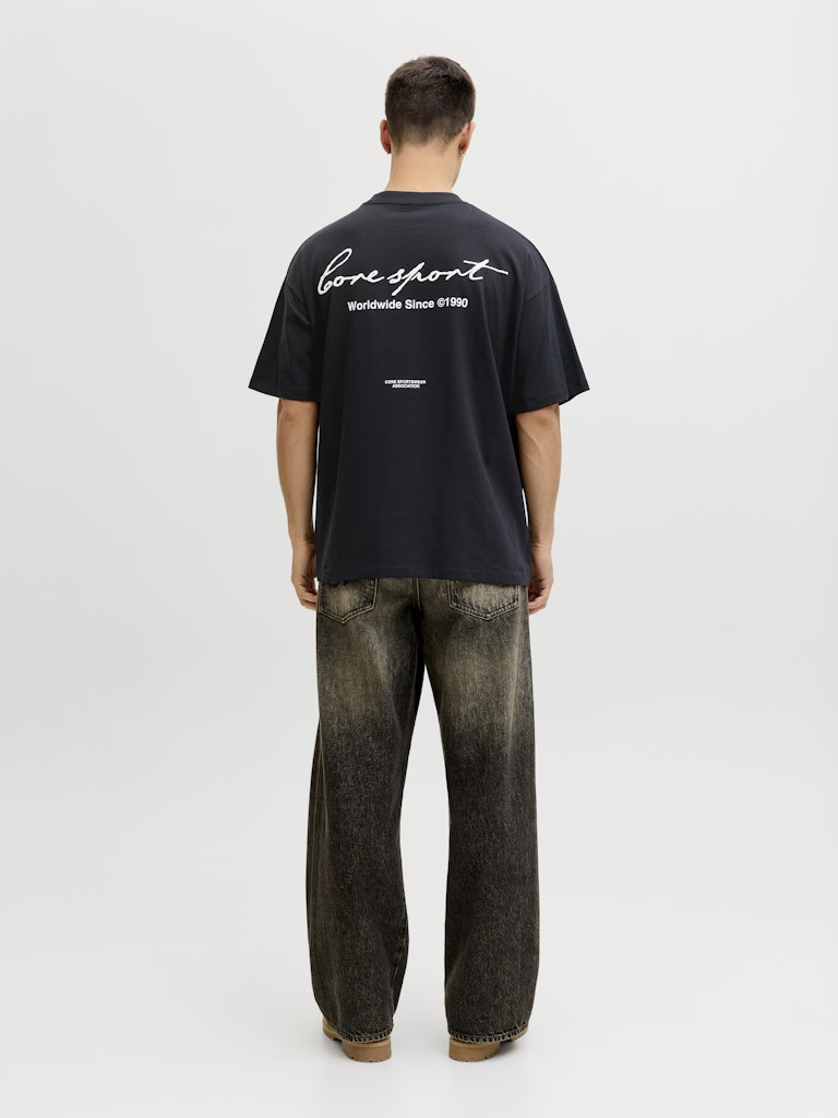 Person wearing a black t-shirt with text on the back, standing against a white background