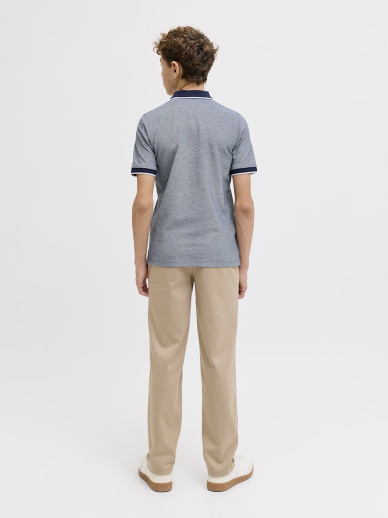 Person wearing a blue polo shirt and beige pants on a white background