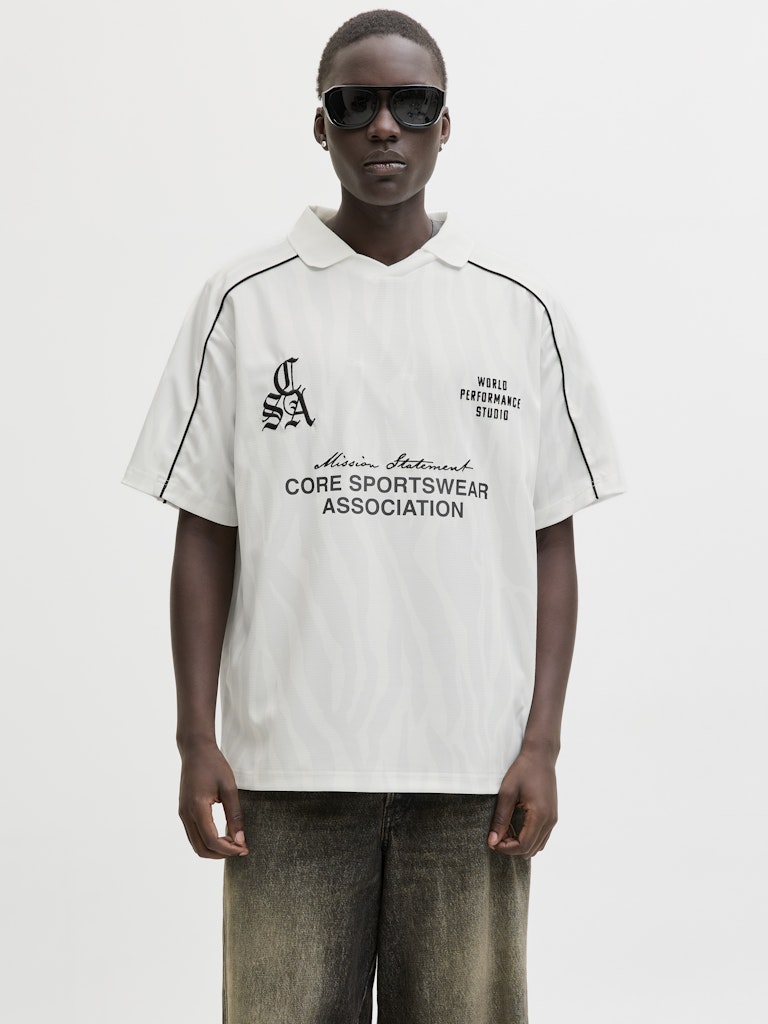 Person wearing a white sports polo shirt with text and logos on a white background