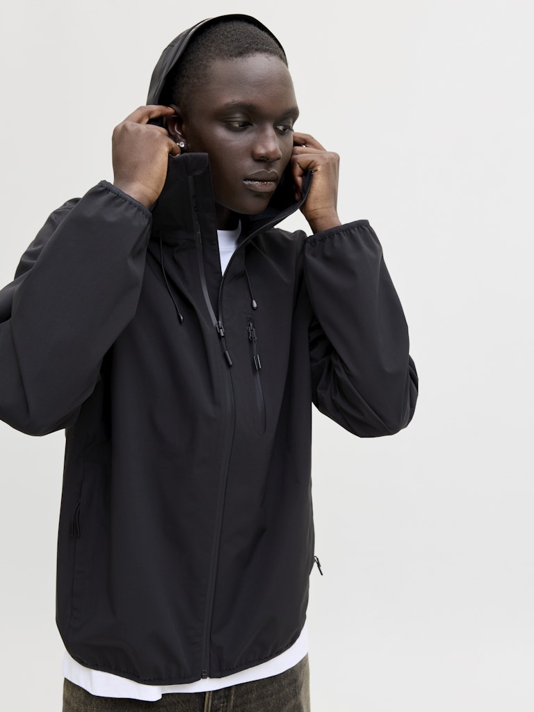 Person wearing a black jacket with a hood on a white background