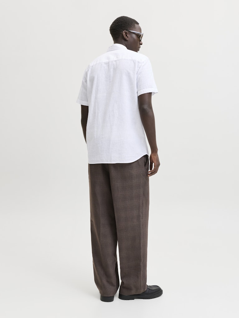 Person wearing a white shirt and brown pants on a plain background