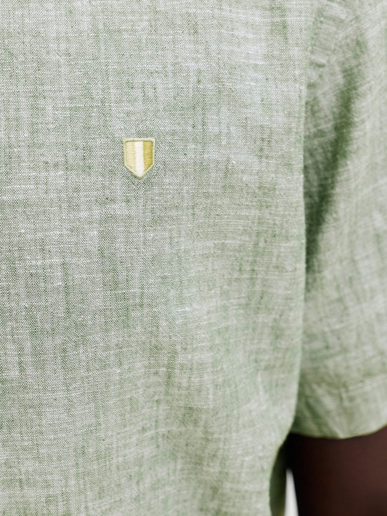 Close-up of a green textured shirt with a small logo on the chest.