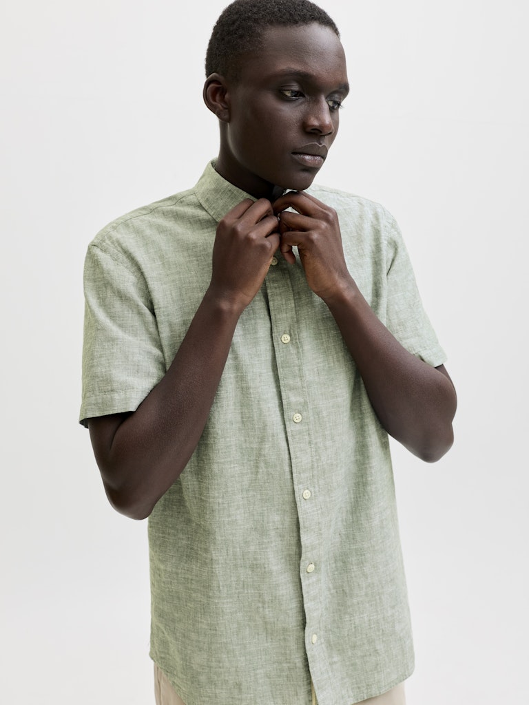 Man wearing a light green shirt against a plain background