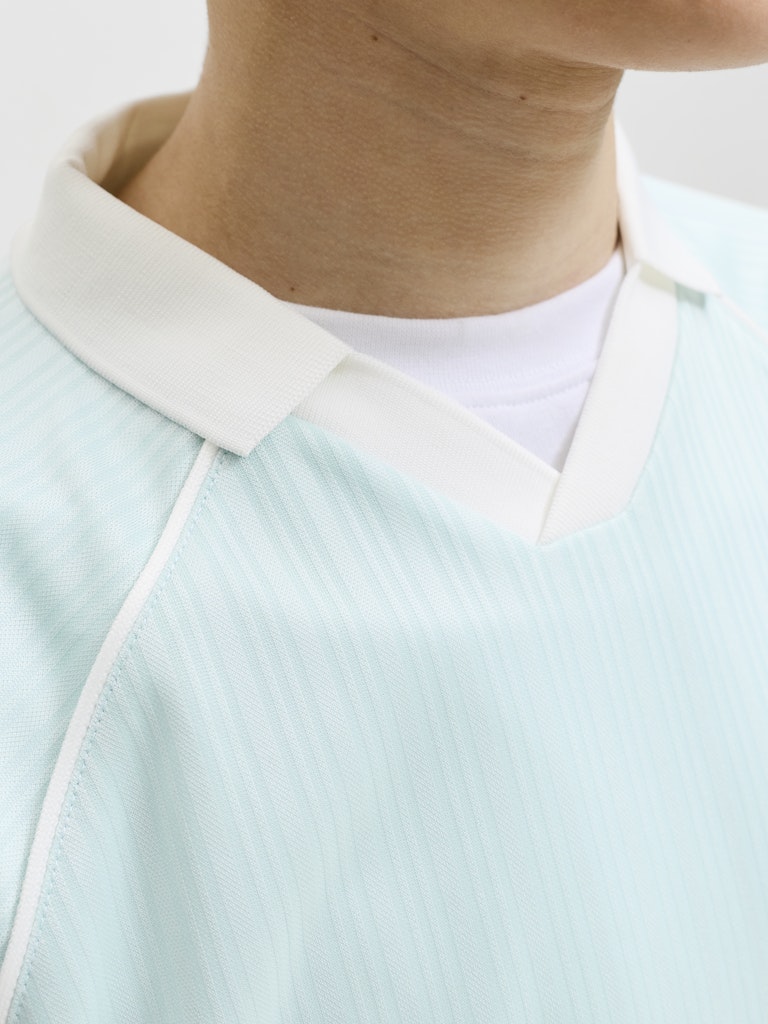 Light blue football polo shirt with white trim worn by a person