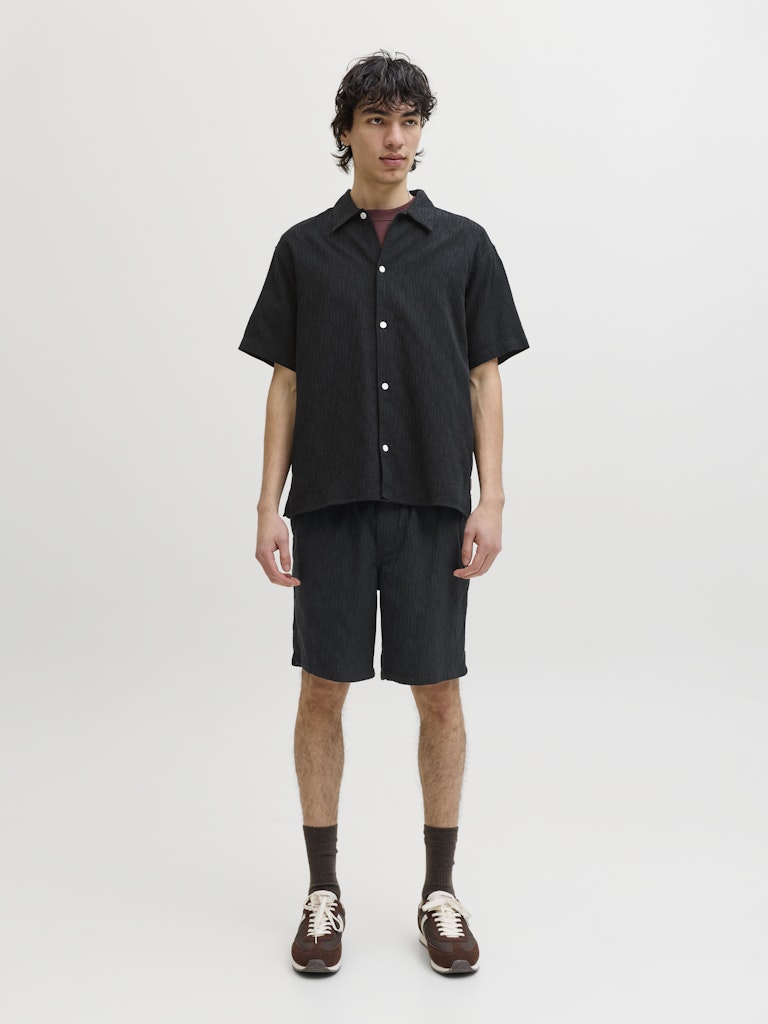 Person wearing a black shirt and shorts set on a white background