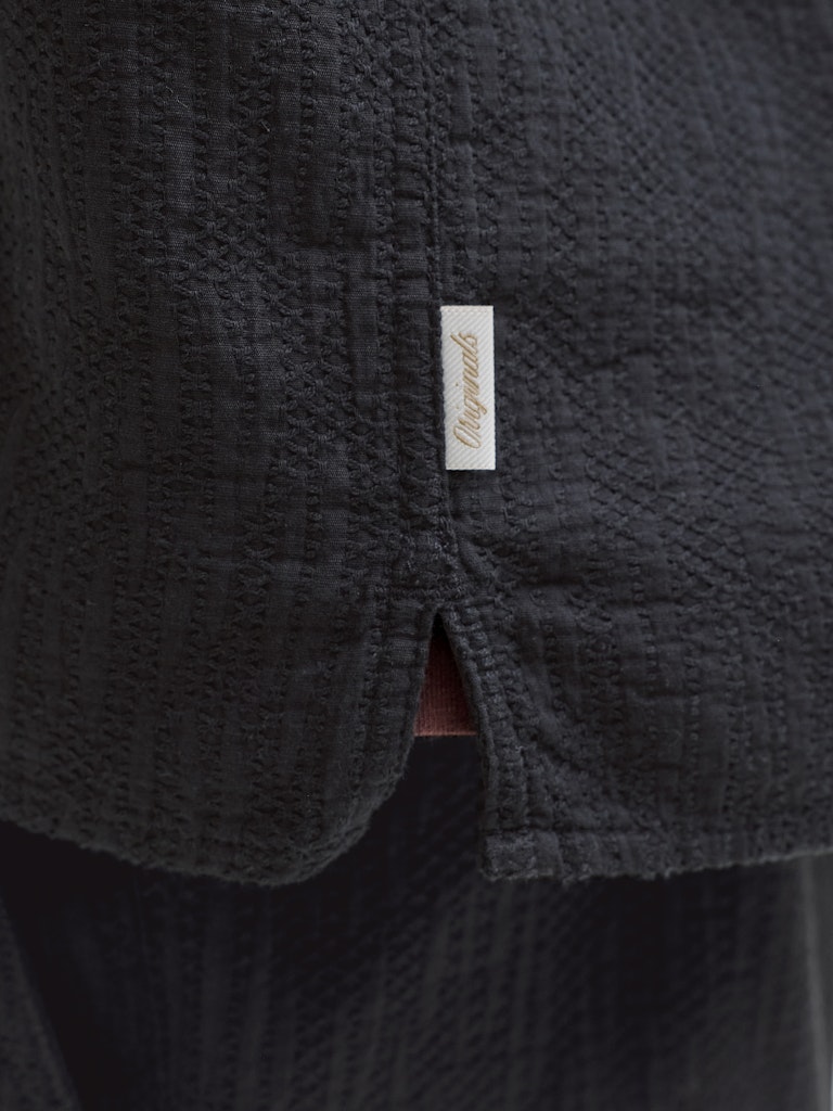 Close-up of a textured dark fabric with a brand label on a black background