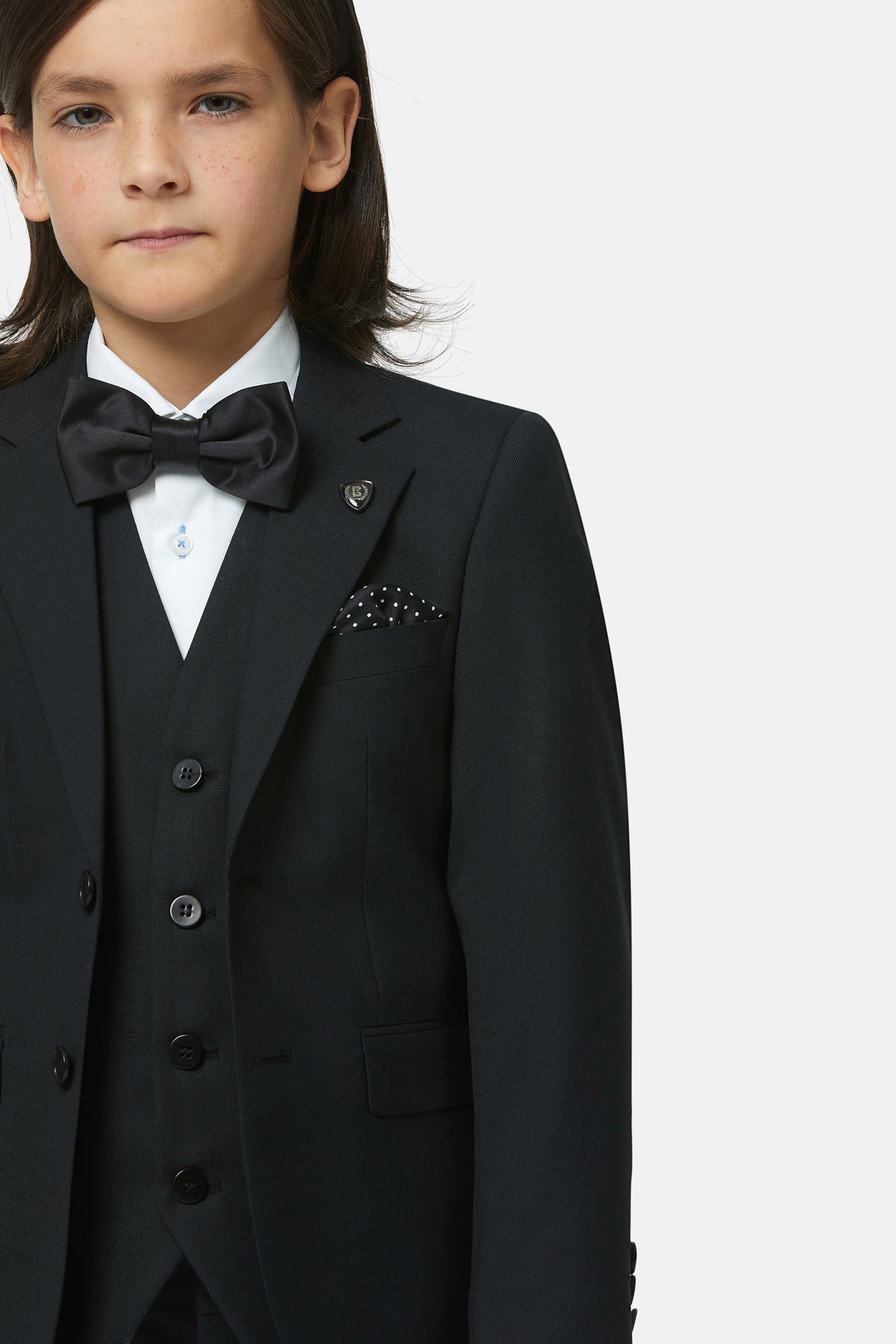 Child wearing a formal black suit with a bow tie on a white background