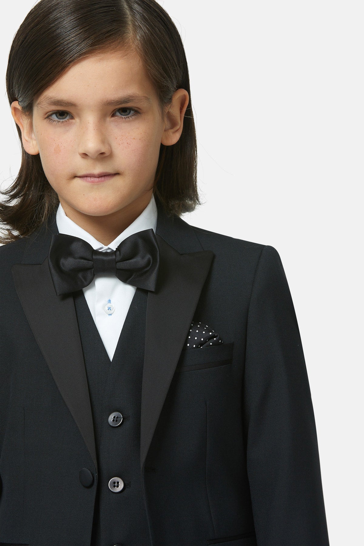 Young boy in a formal black suit with bow tie on a white background