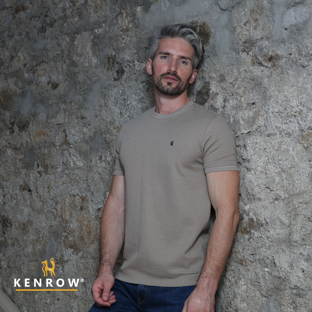 Man wearing a beige t-shirt against a stone wall with 'Kenrow' branding.