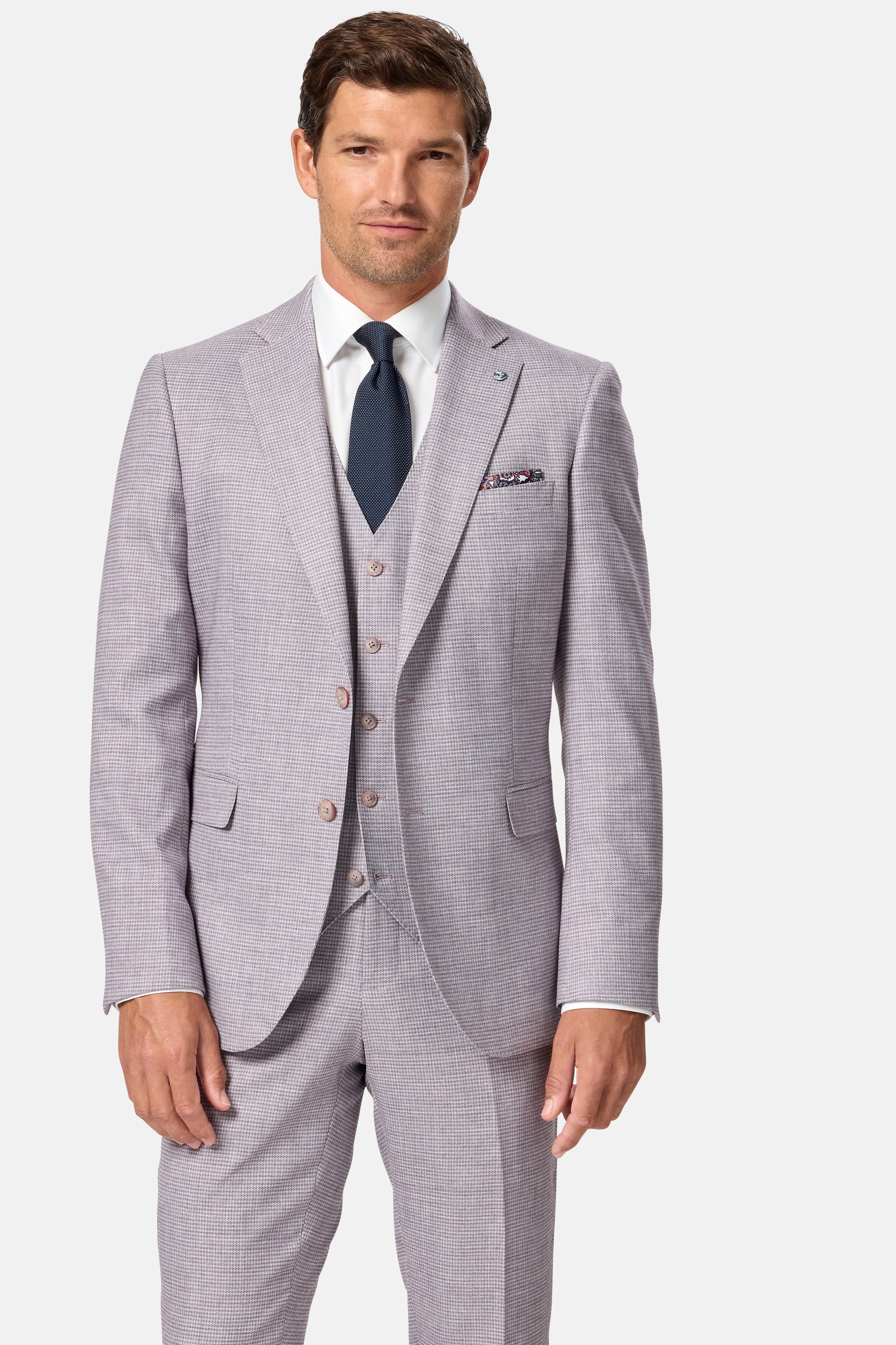 Man wearing a blush checkered suit with a white shirt and dark tie on a white background