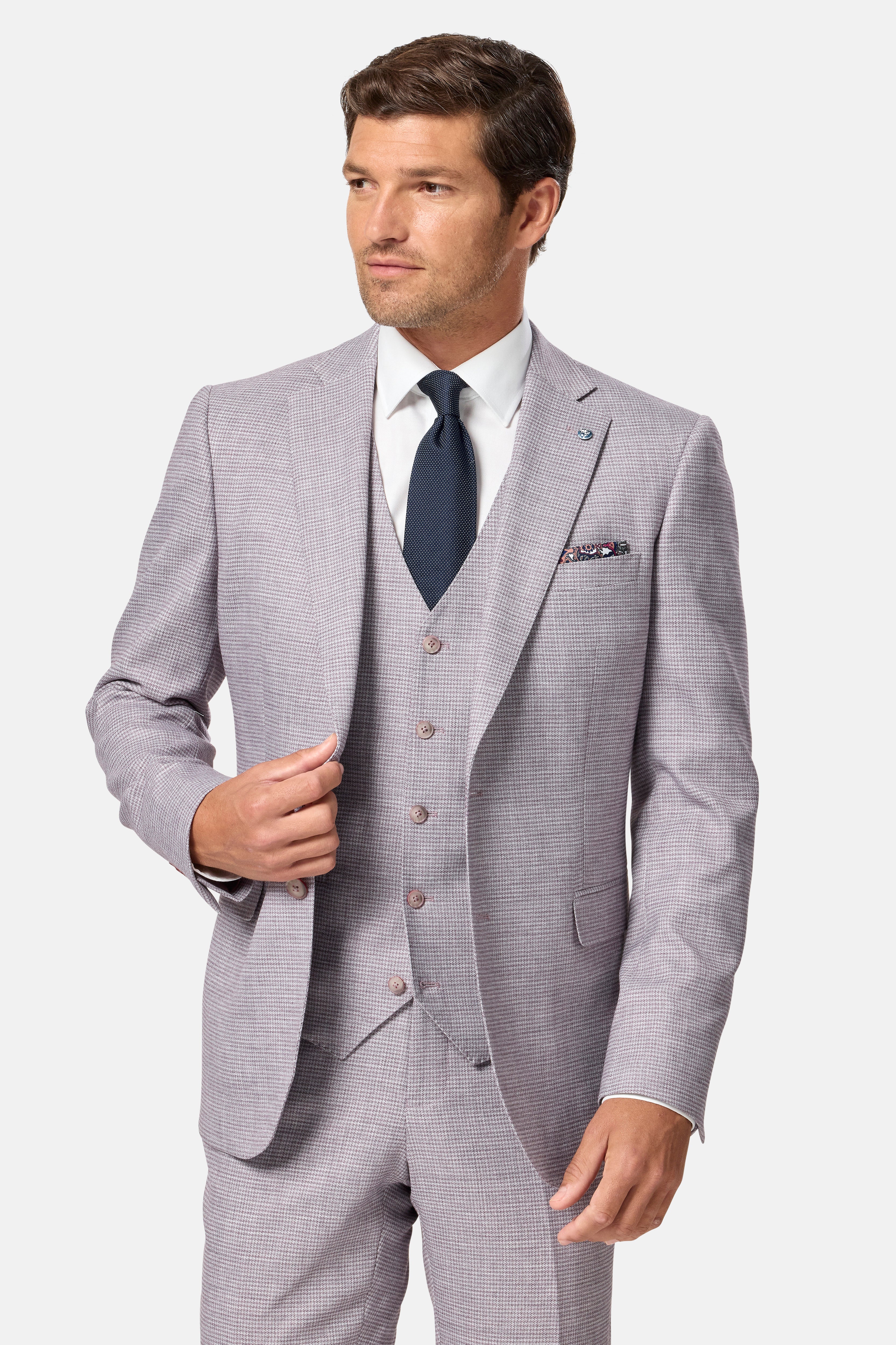 Man wearing a blush checkered suit with a white shirt and dark tie on a light gray background
