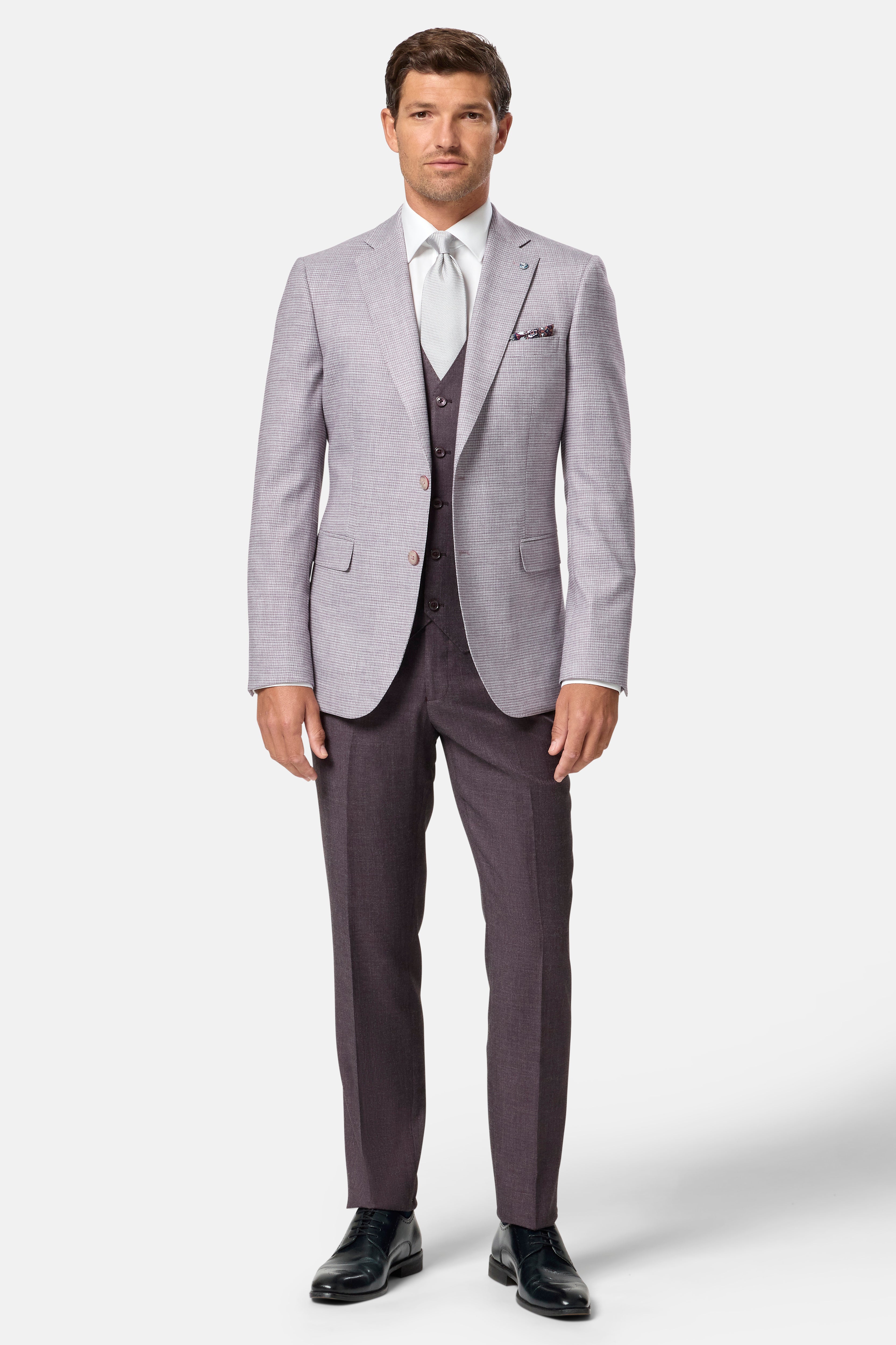 Man wearing a blush suit with a white shirt and black shoes on a white background