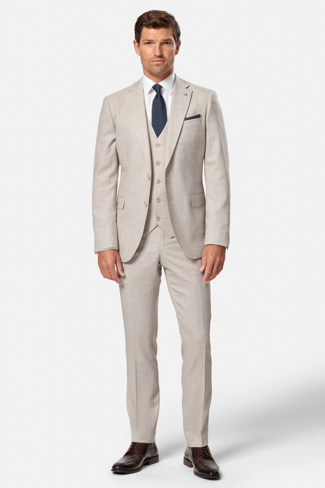 Man wearing a beige suit with a blue tie on a white background