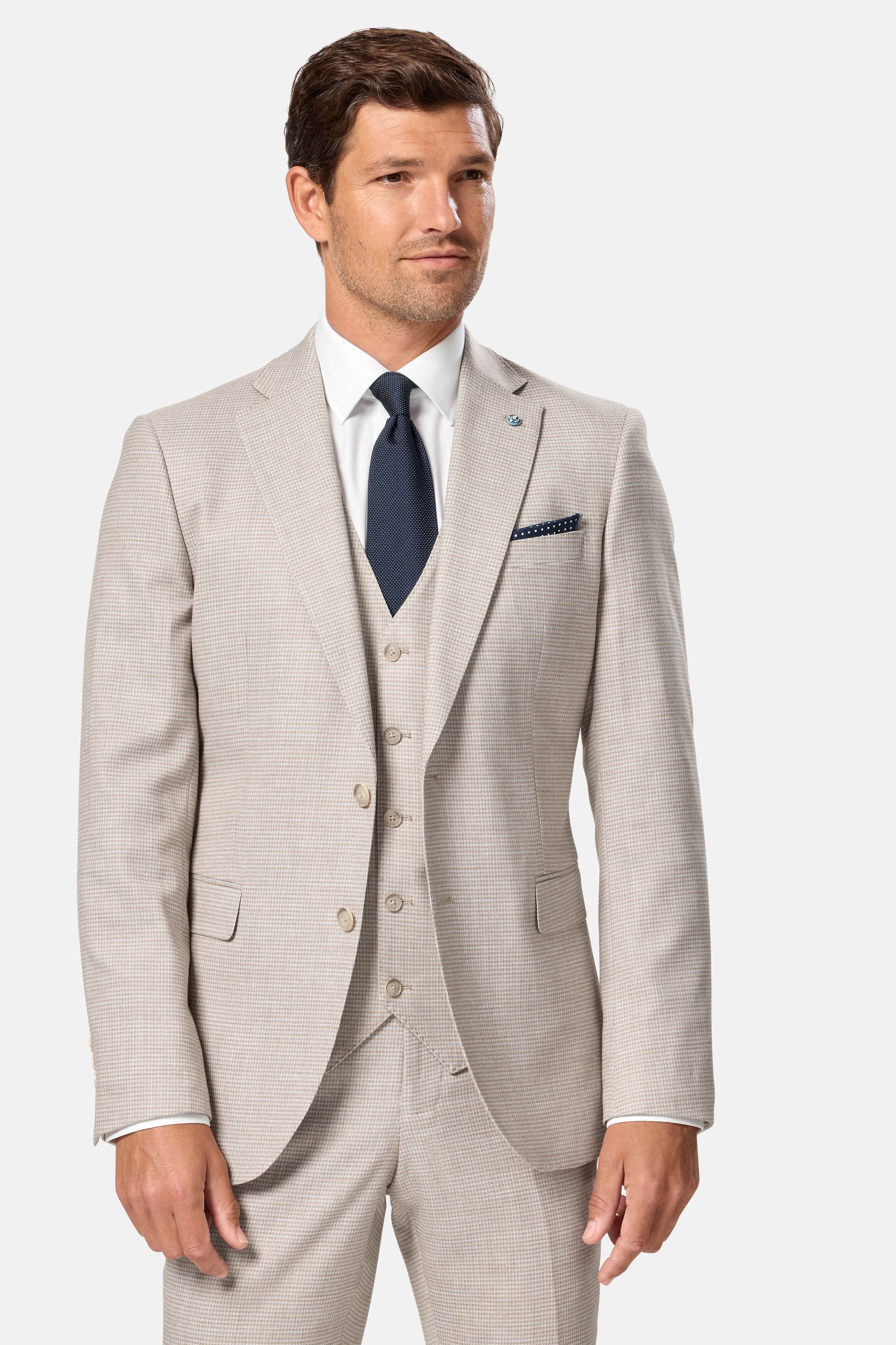 Man wearing a light stone suit with a white shirt and dark tie on a white background