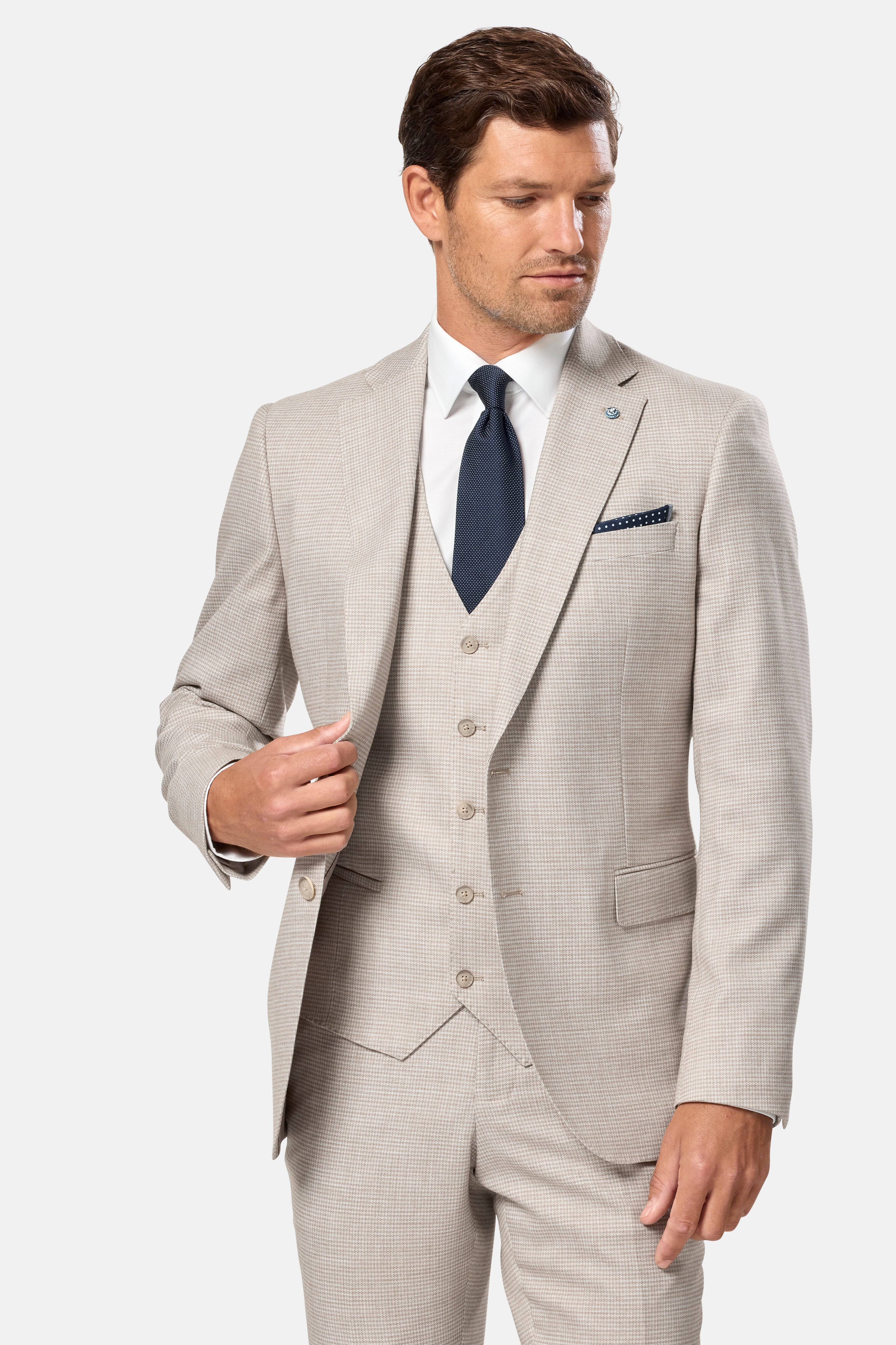Man wearing a light stone suit with a white shirt and navy tie on a white background
