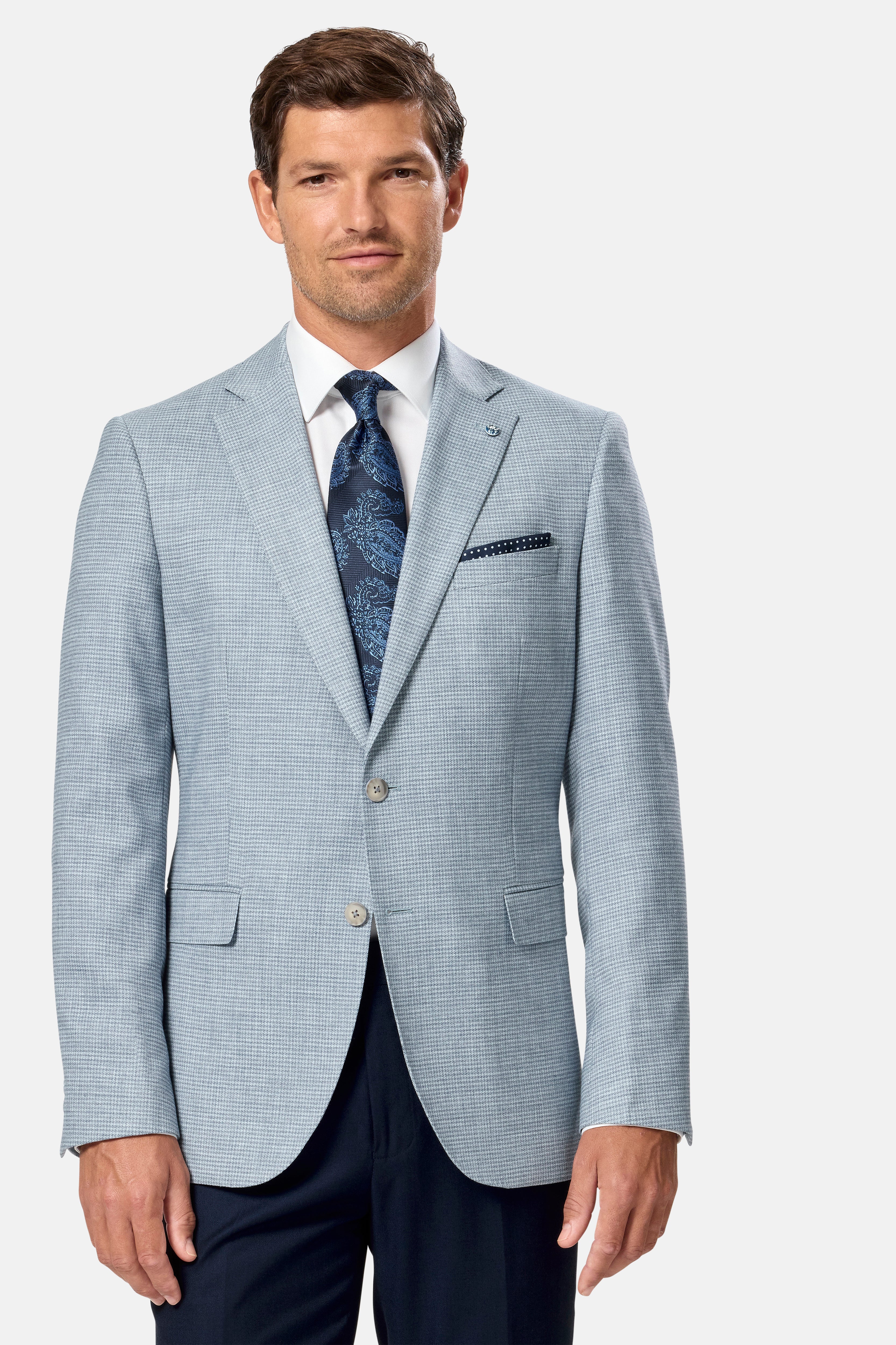 Man wearing a light blue checkered blazer with a white shirt and dark tie on a white background