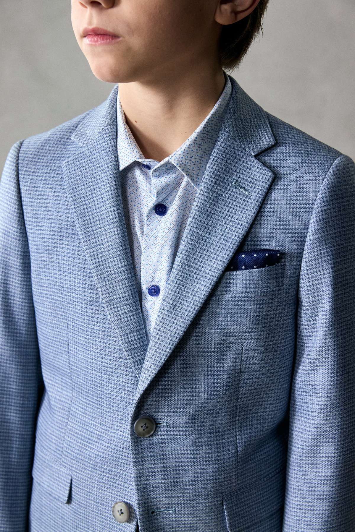Person wearing a light blue checkered suit with a white shirt and dark tie.