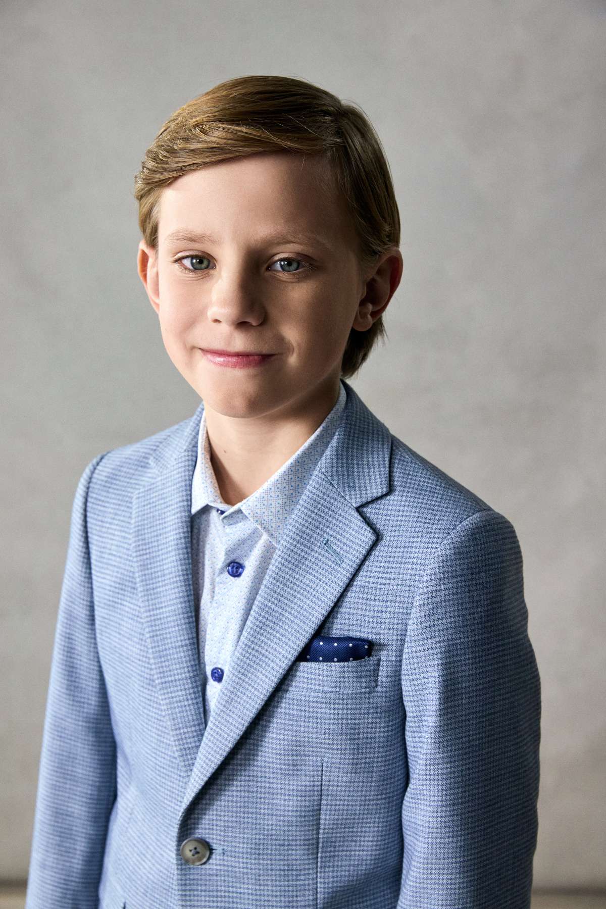 Young boy in a light blue suit with a gray background