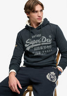 Superdry Vintage Logo Classic Hoodie in Eclipse Navy seated model view