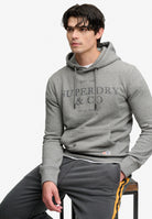 Superdry 1954 Company Relaxed Hood in Dark Vintage Grey Marl seated model view