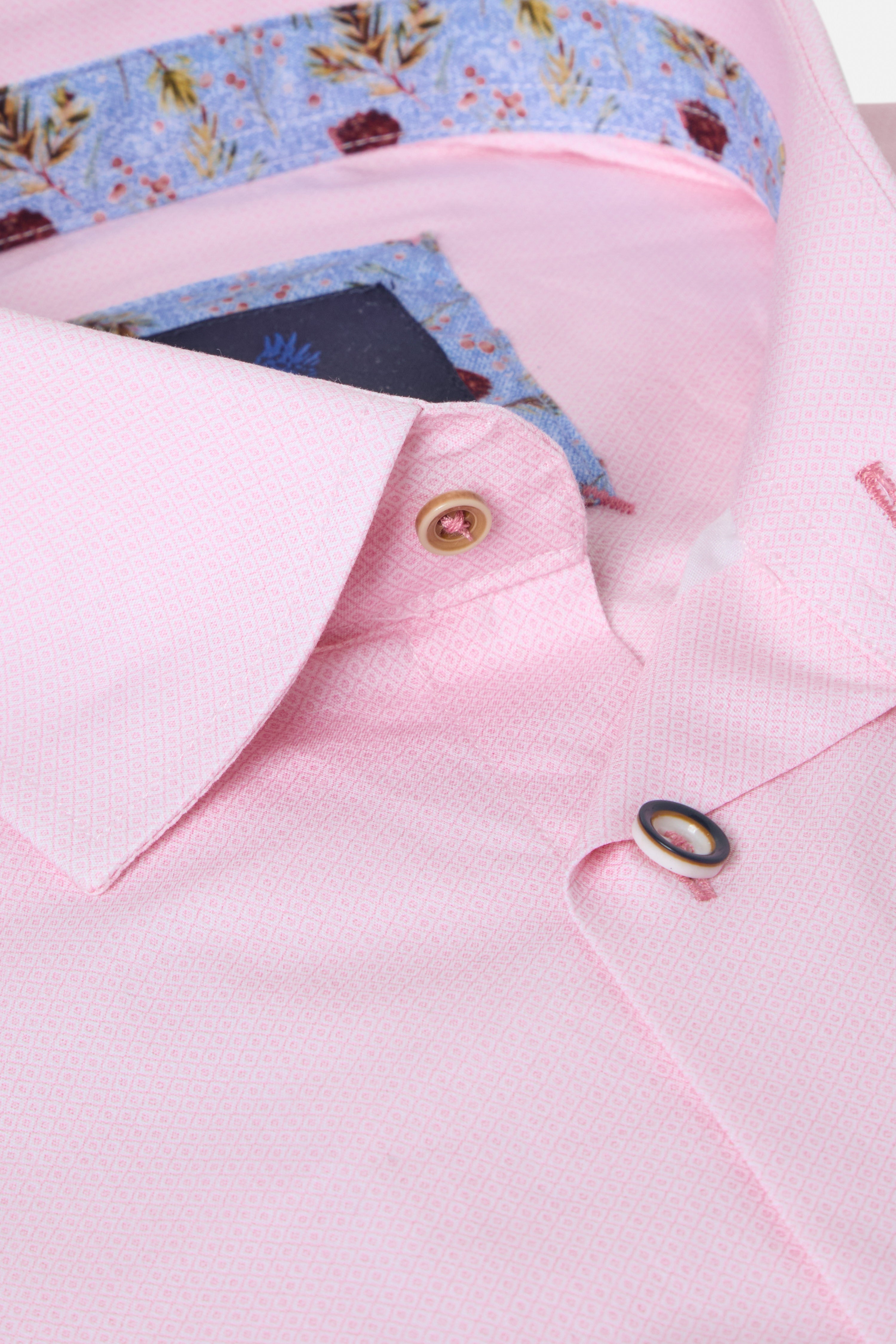 Close-up of a pink shirt with floral-patterned fabric peeking out from underneath.