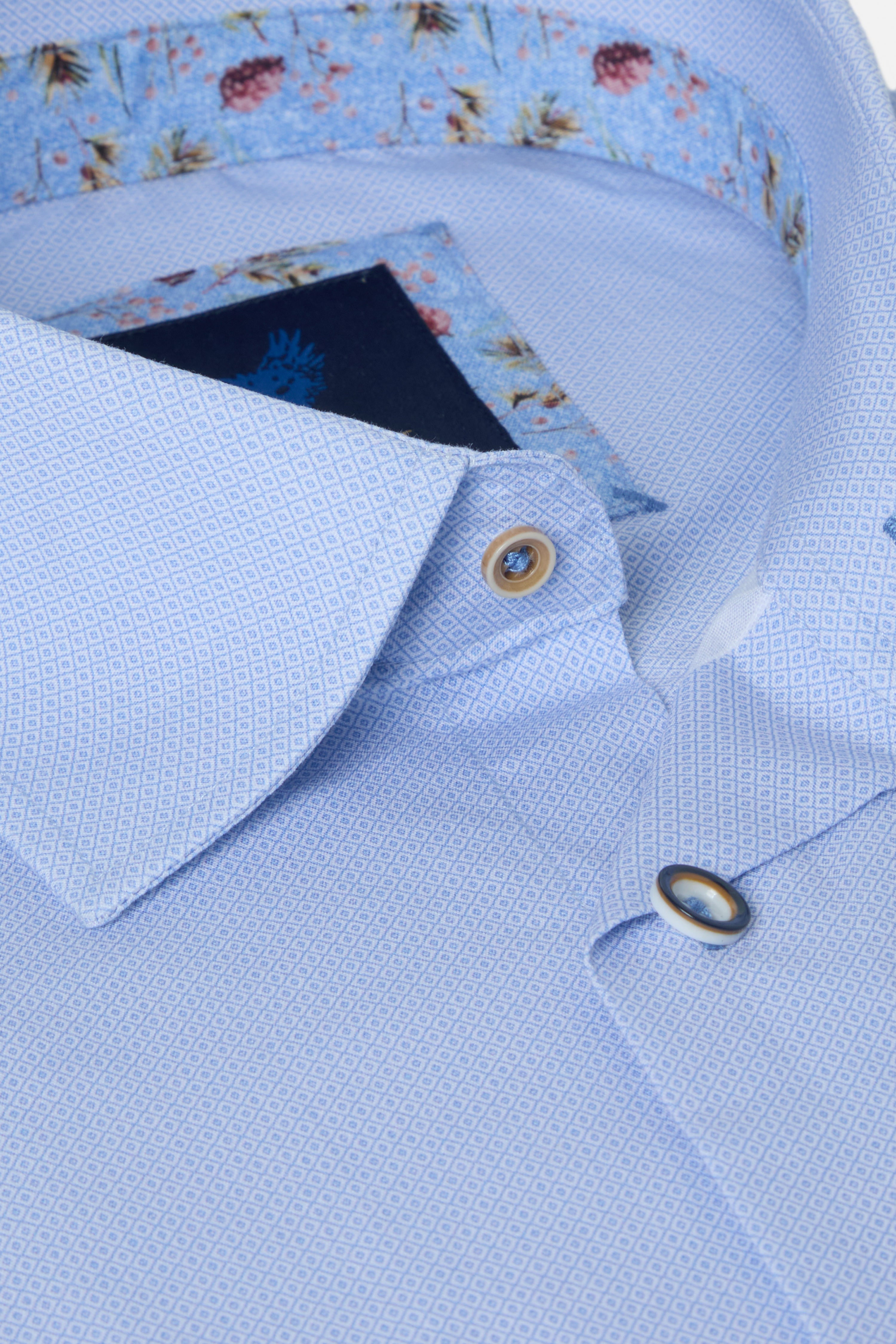 Close-up of a light blue shirt with floral collar and cuff details.