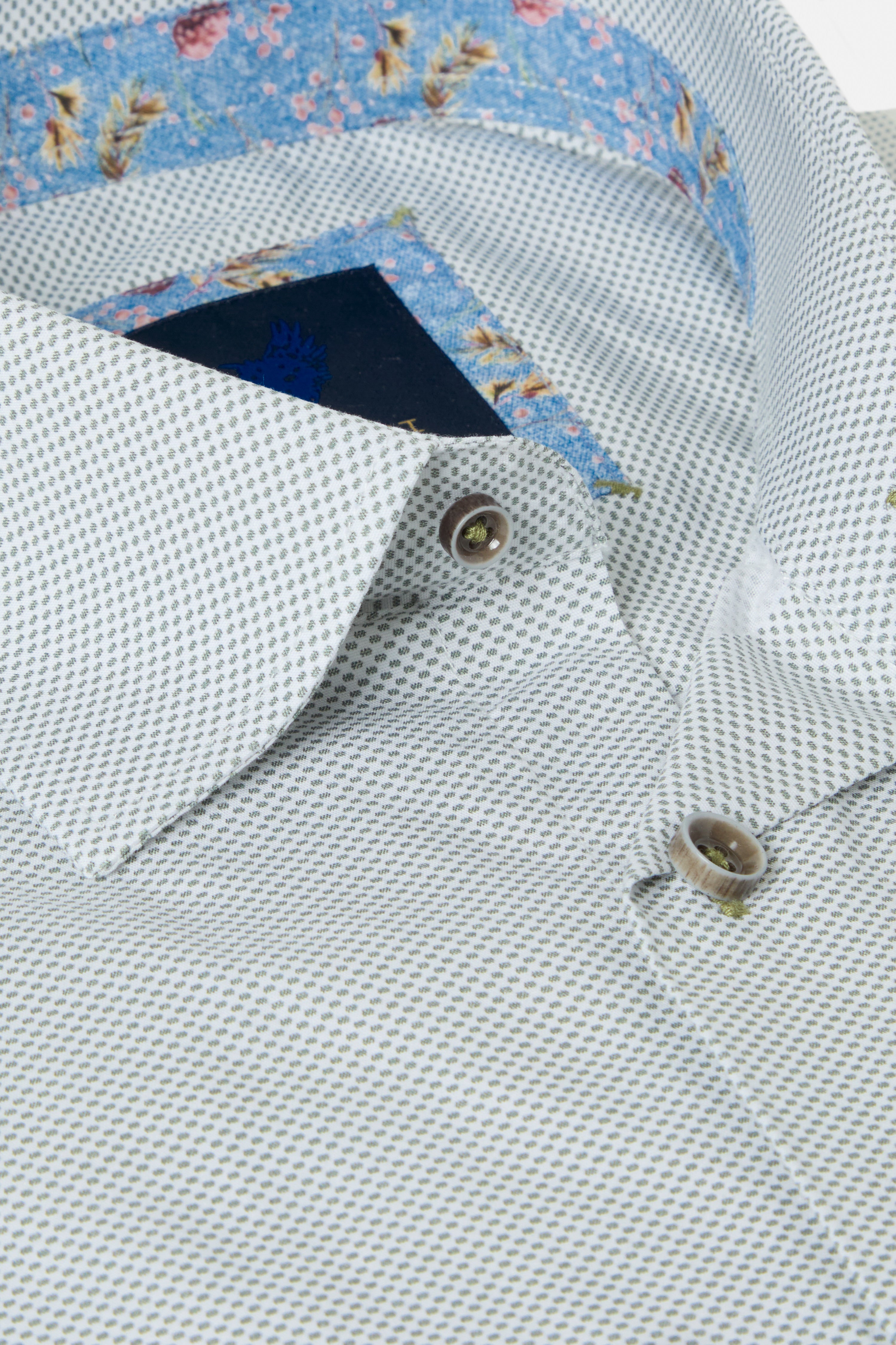 Folded sage green shirt with floral lining on a white background-Collar close up