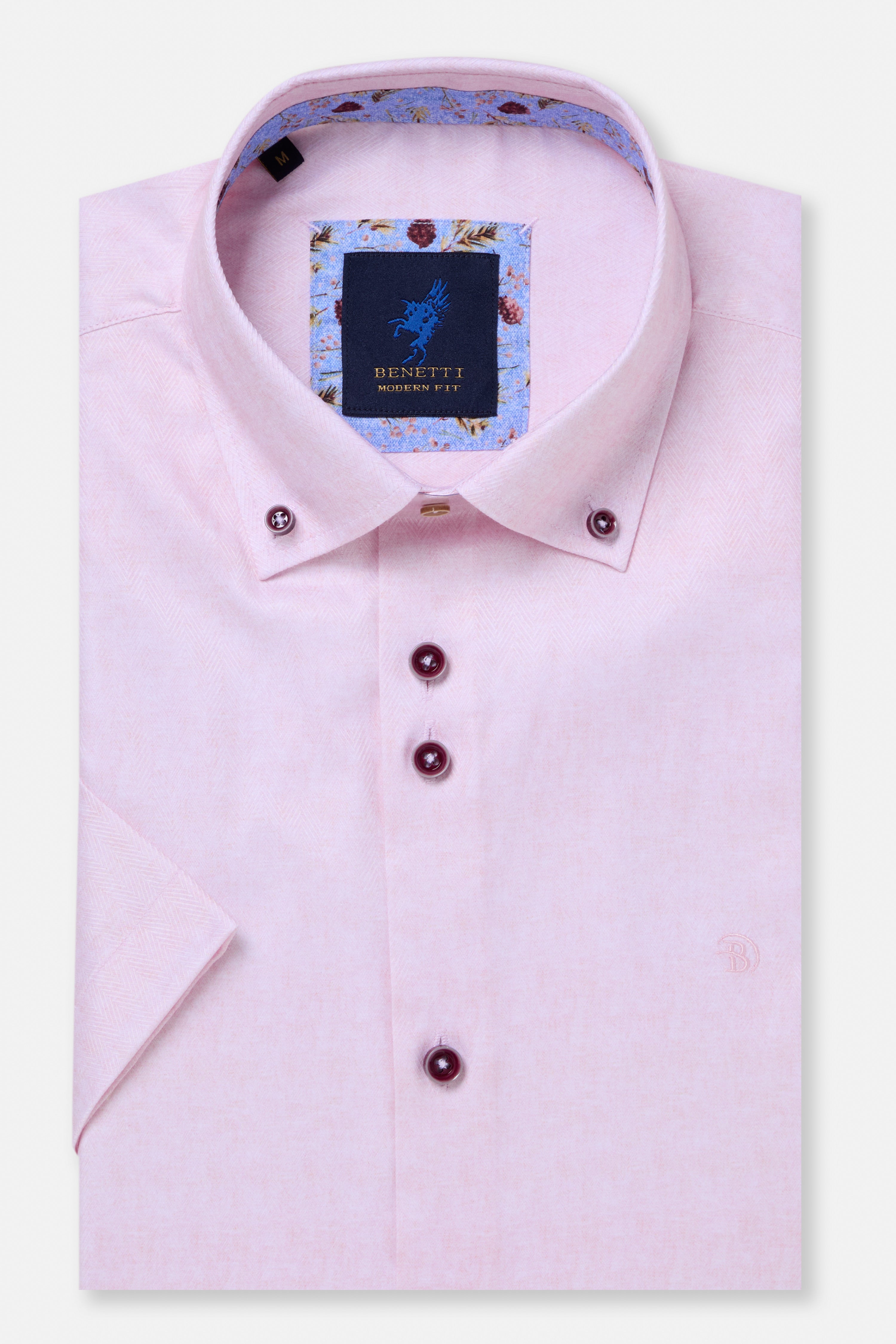 Folded light pink dress shirt with a brand label on a white background