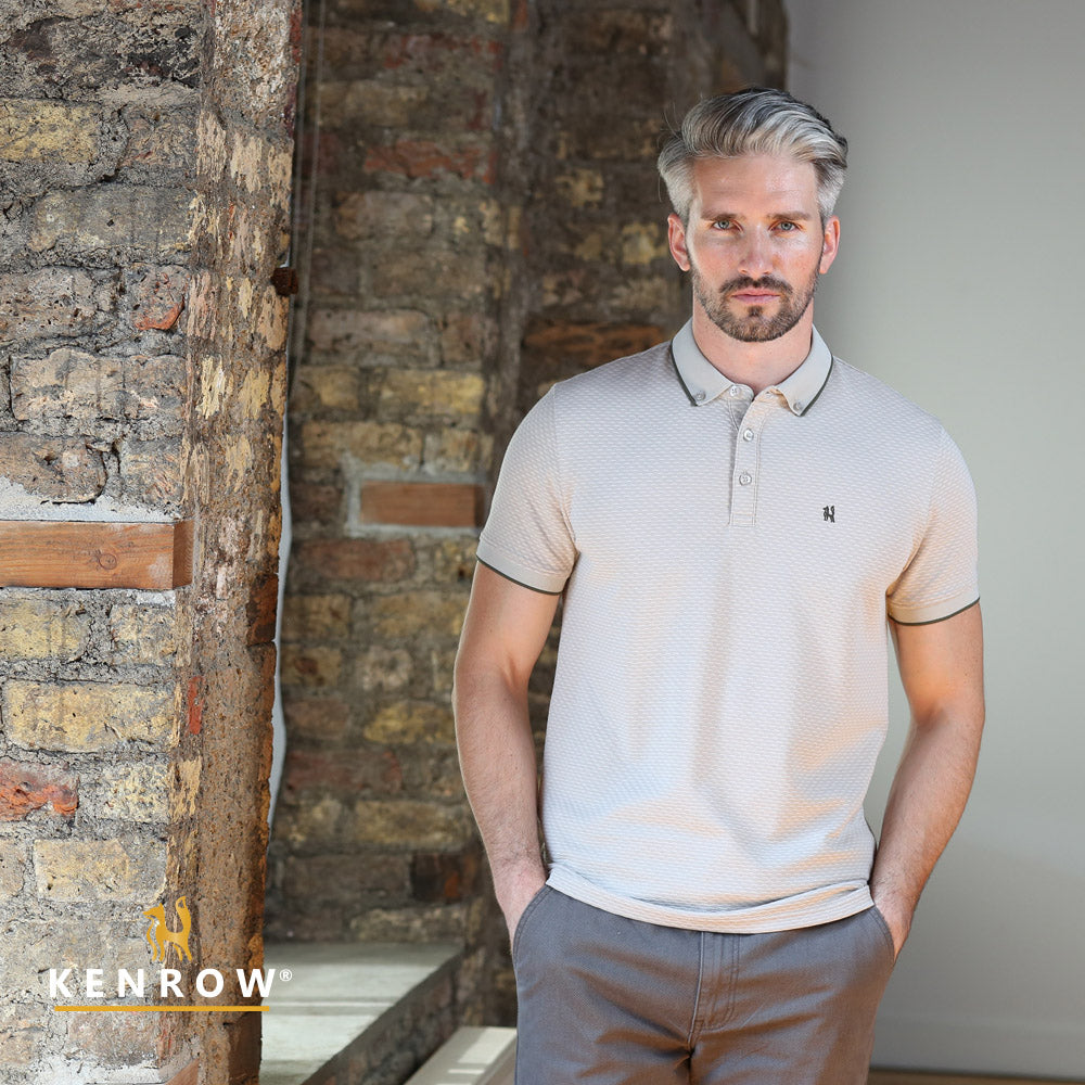 Man wearing a light-colored polo shirt standing against a brick wall with 'KENROW' branding.