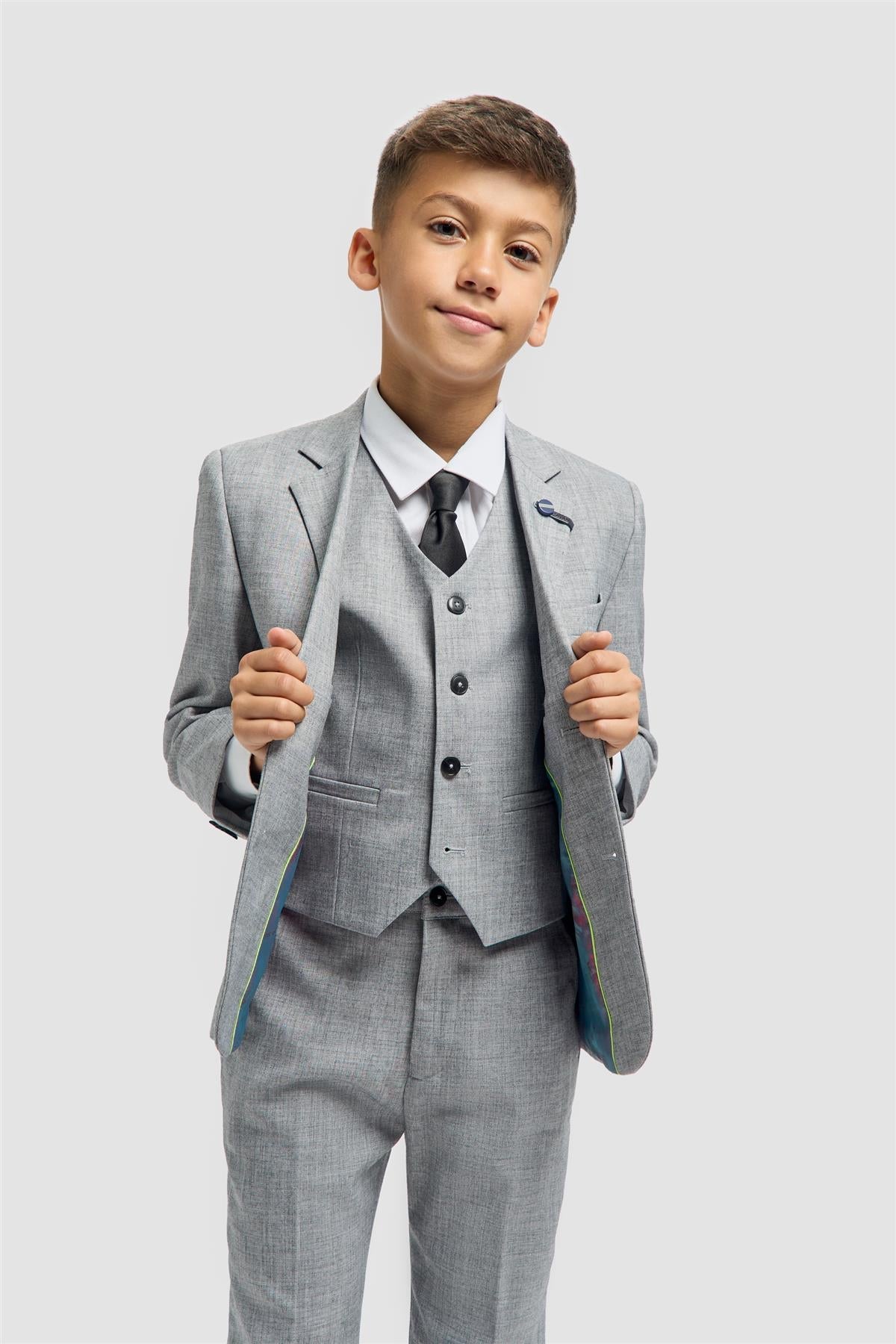 Young boy wearing a gray suit with a white shirt and black tie on a light gray background