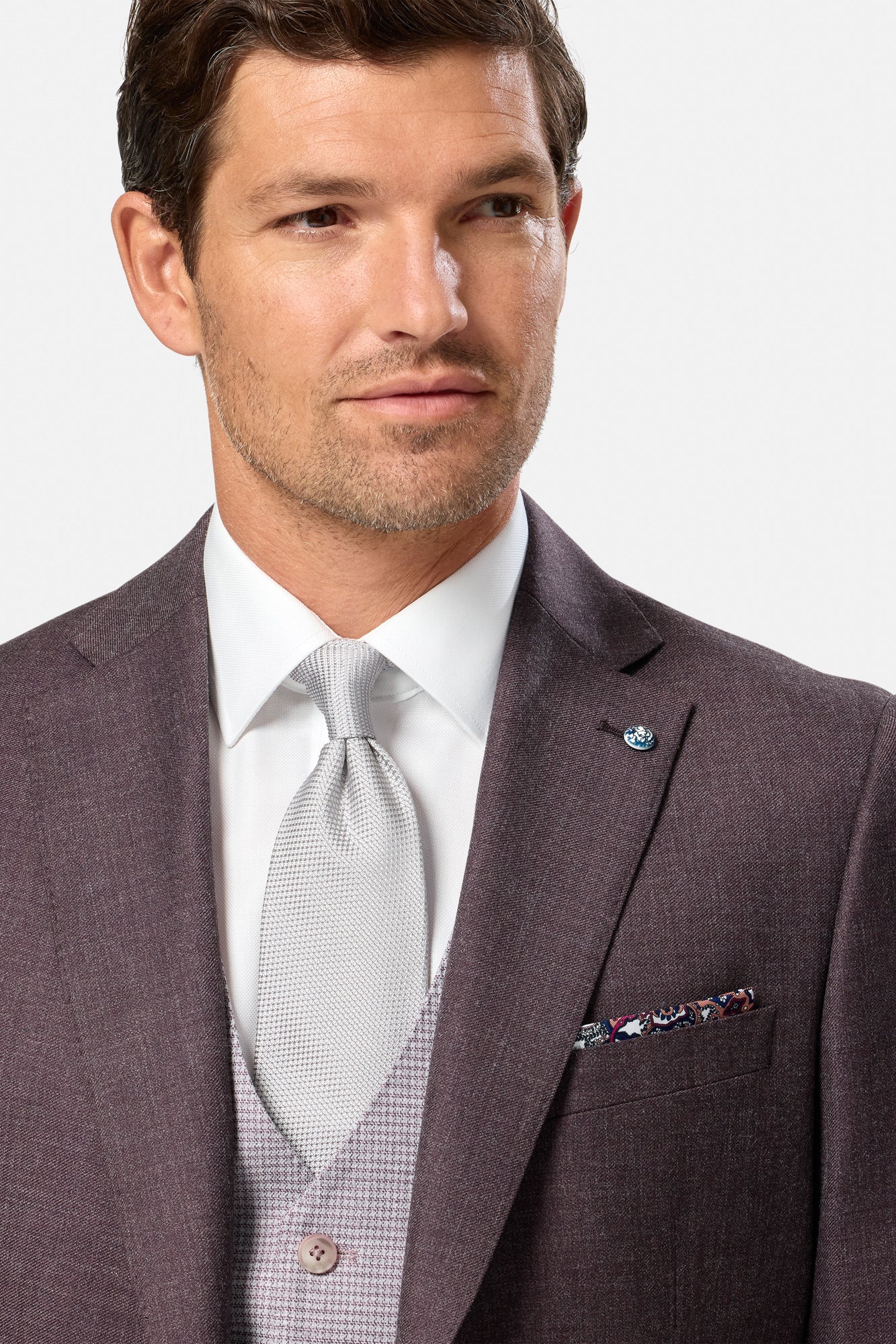 Man wearing a grape suit with a white shirt and gray tie on a light gray background