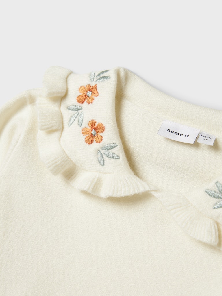Cream-colored sweater with floral embroidery on a white background