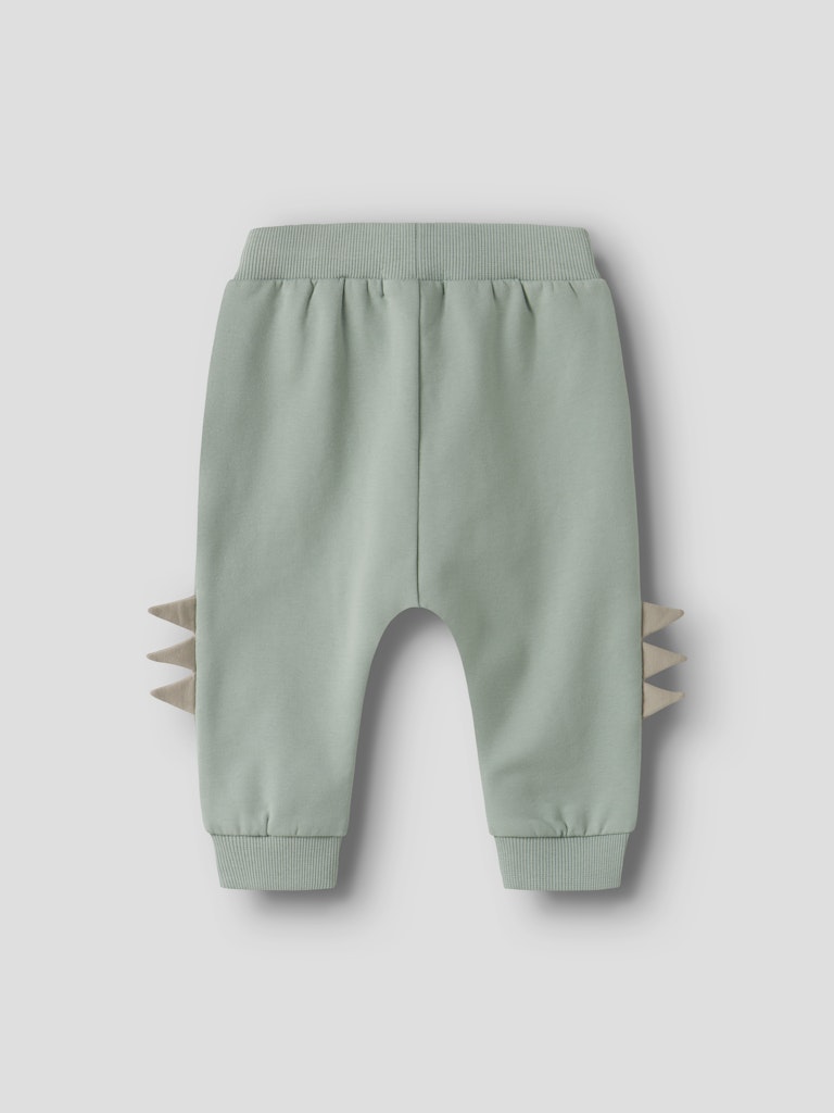 Light green baby pants with spike details on a light gray background