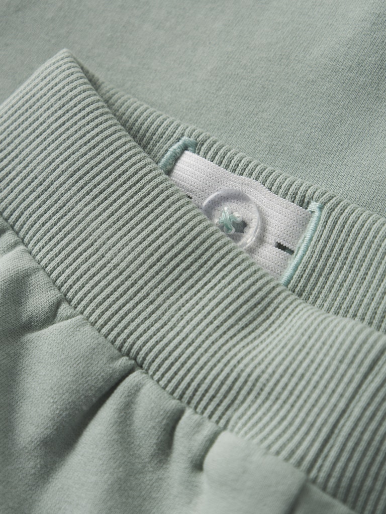 Close-up of a light green fabric with a button adjuster waistband.