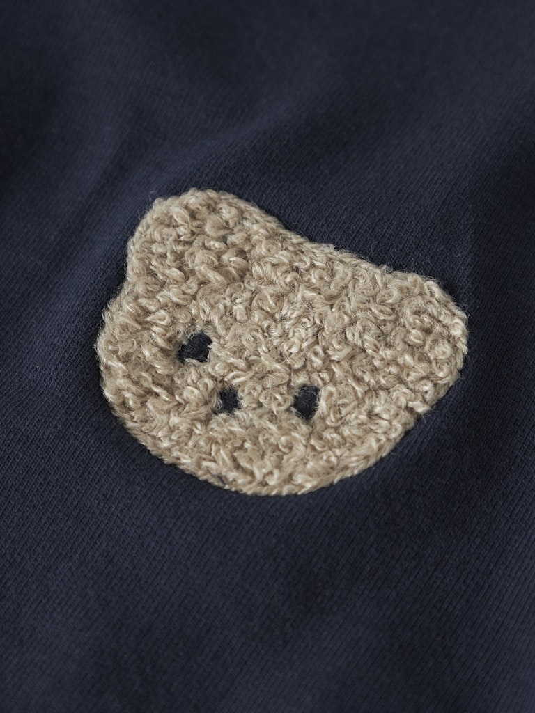 Beige crocheted heart-shaped patch on a dark fabric background