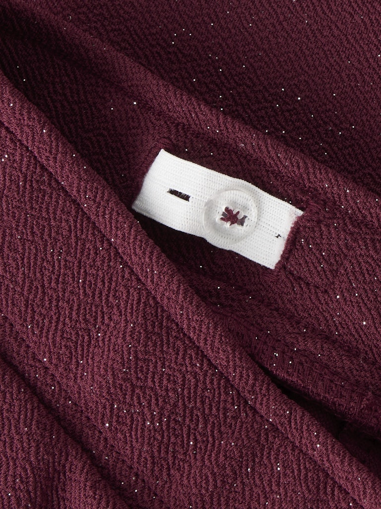 Close-up of a maroon fabric with a brand label.