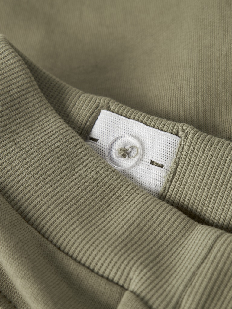Close-up of a green fabric with a white label on a matching green background