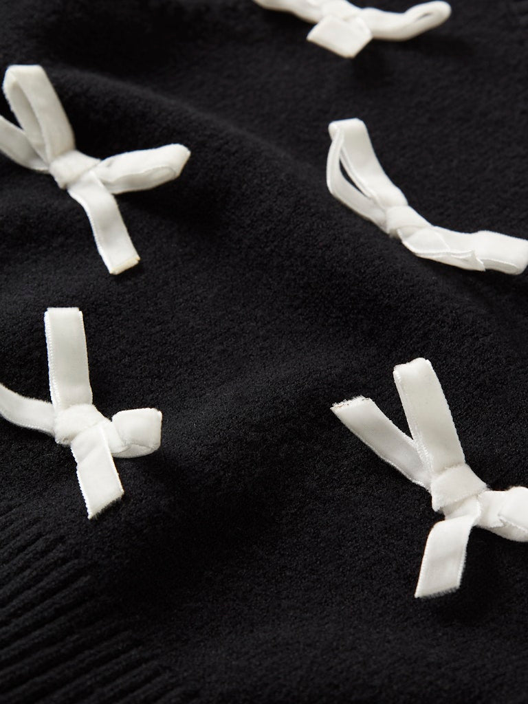Black fabric with white ribbon-like decorations on a dark background