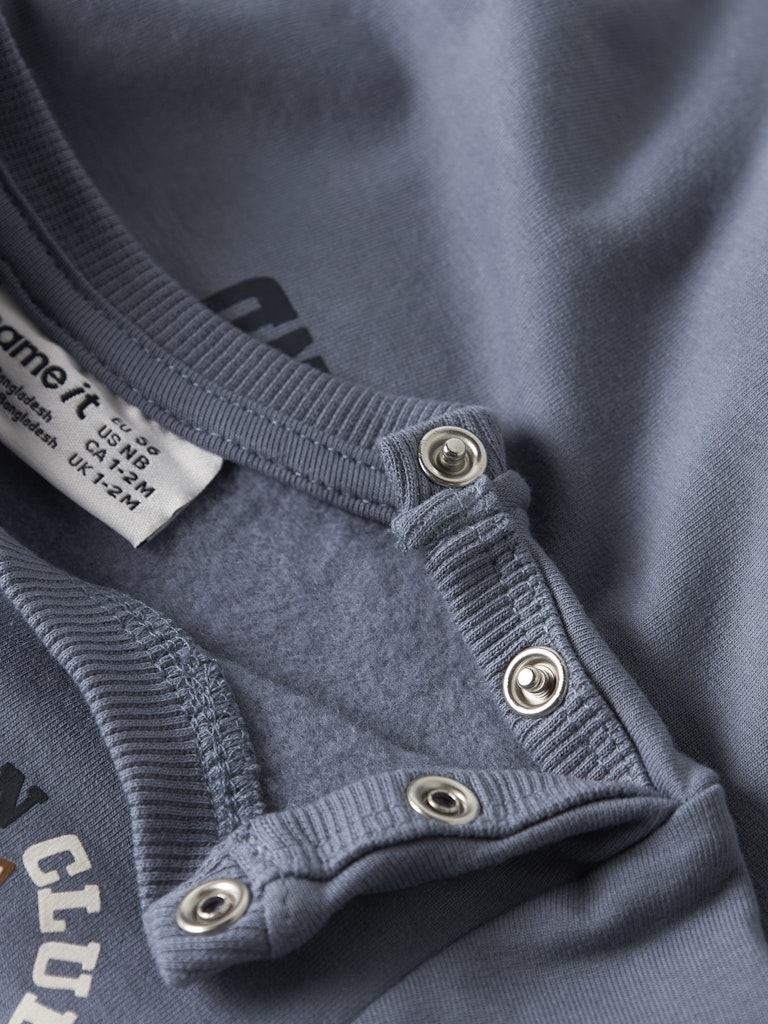 Close-up of a blue garment with button details and a brand label.