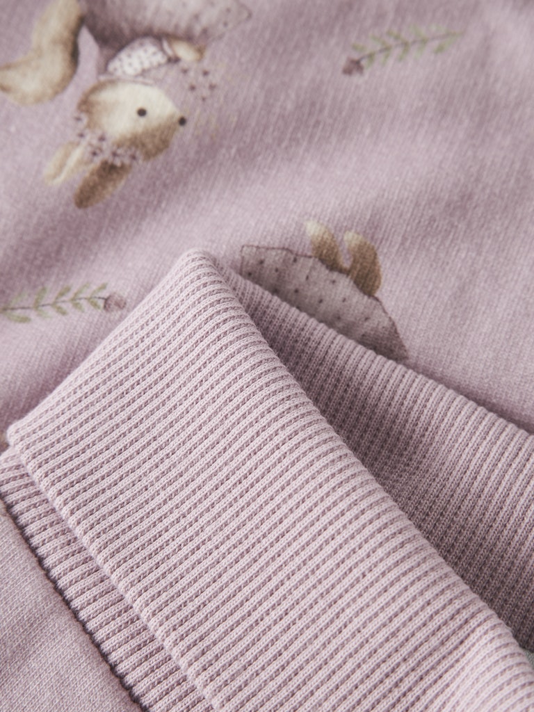 Close-up of textured fabric with squirel pattern on a soft pink background