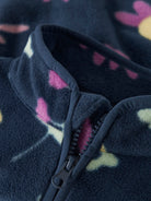 Close-up of a dark blue fleece jacket with pink and yellow floral patterns on a blurred background.